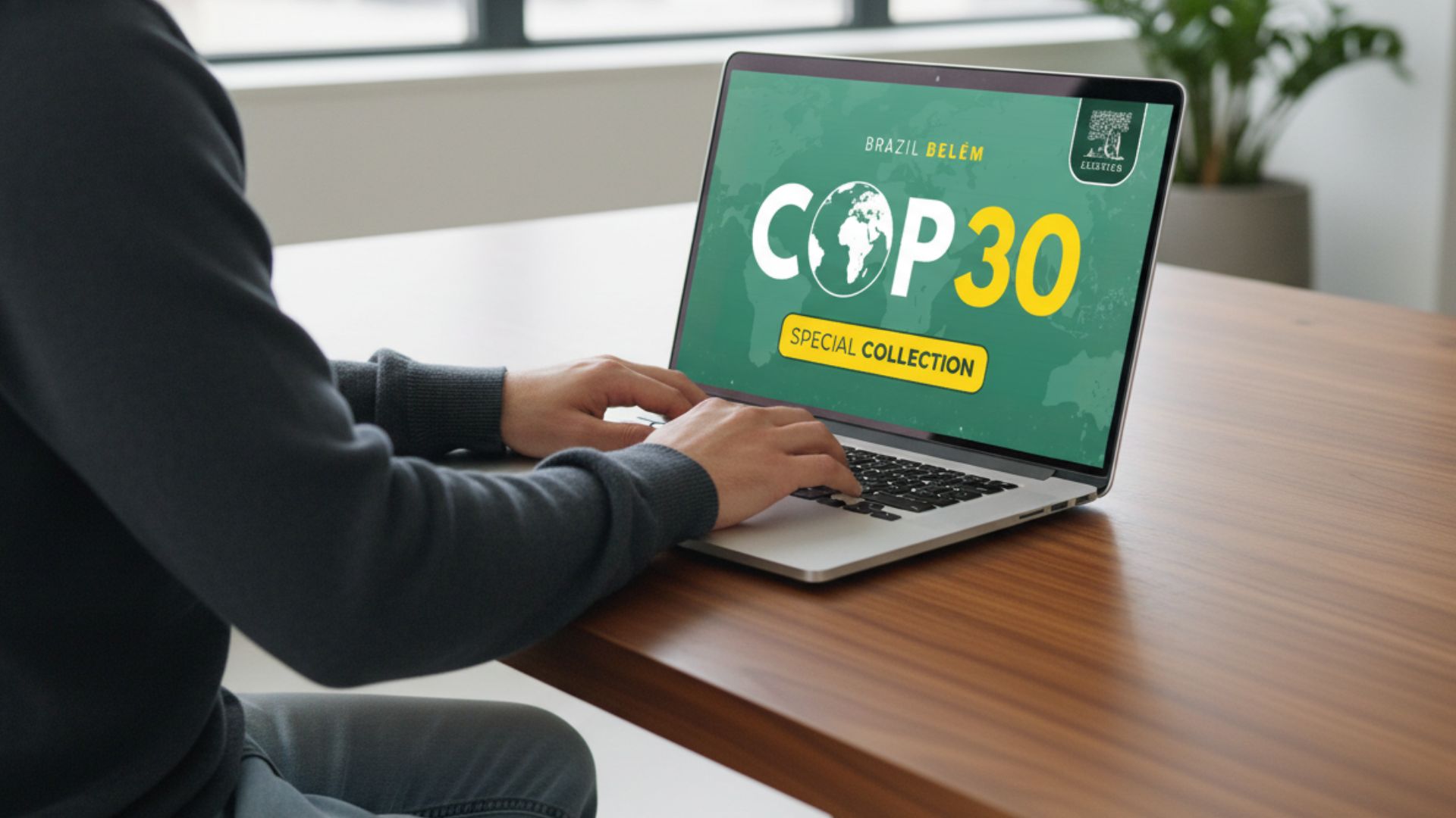 A man working on a laptop that is placed on a brown wooden desk.  On the screen is the COP 30 special issue title.