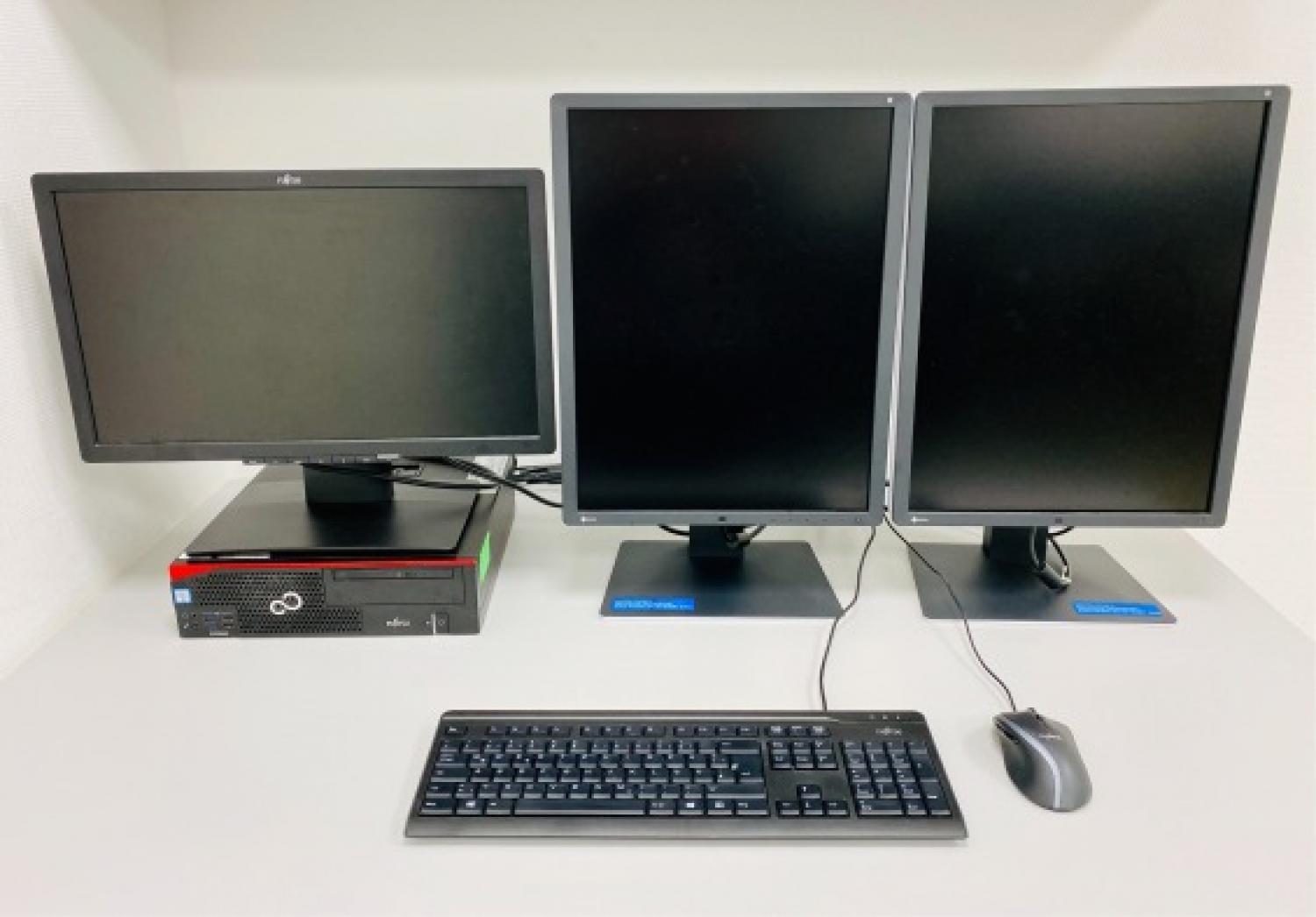 Photography of a representative workstation consisting of a desktop computer, two medical-grade diagnostic monitors and a third monitor for the radiology information system (RIS).